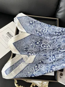 Detail view of premium blue paisley silk scarf elegantly folded on a luxury tray