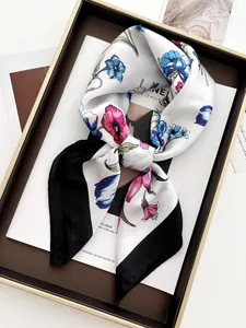 Detailed close-up of floral silk scarf with butterfly prints and black border on a tray