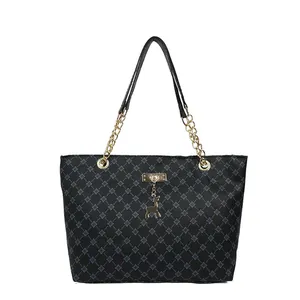 Bolso tote negro con patrones de cruces azules, asas de cadena dorada y colgante de ciervo