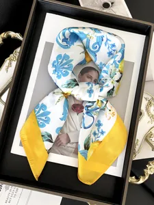 Detailed close-up of silk scarf with blue baroque fruit prints and yellow borders