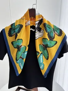 Détail du foulard en soie jaune avec imprimé papillon sur un t-shirt noir suspendu