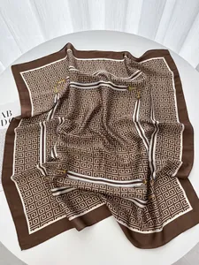 Detail of silk-like coffee square scarf featuring geometric patterns and golden chain motifs