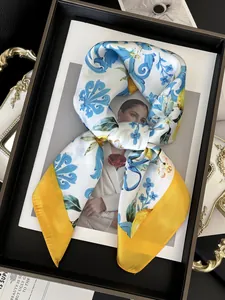 Detailed view of silk square scarf with blue Mediterranean floral print and yellow border