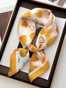 Detail of silk-like square scarf featuring colorful heart patterns tied in a bow
