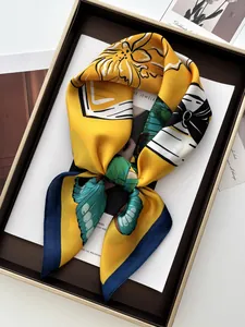 Gros plan du foulard en soie jaune avec motifs papillons sur plateau doré