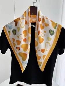 Detailed close-up of a white silk scarf with orange watercolor hearts on a black shirt