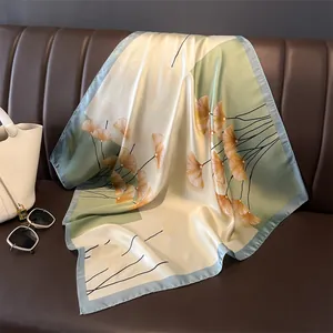 Detail eines Seidenschals mit Ginkgoblattmuster elegant auf Ledersofa drapiert