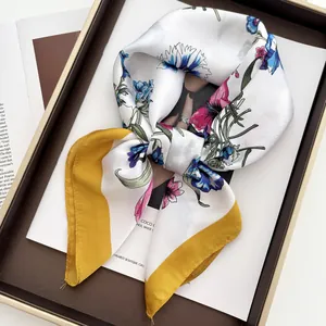 Floral silk-like scarf with blue flowers and mustard yellow border on a magazine