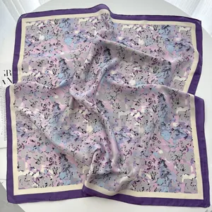 Detailed view of square silk scarf with purple floral print and elegant dark borders