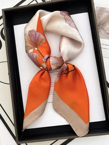 Detail eines eleganten Satinschals mit Ginkgoblatt-Druck in Orange und Beige als Schleife