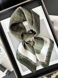 Detalle del pañuelo de seda verde con estampados geométricos y motivos florales rojos