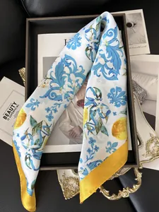Close-up of silk scarf with Sicilian lemon print and blue floral patterns on dark tray