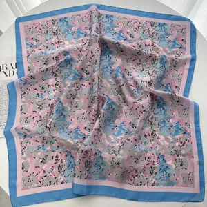 Close-up of lightweight square silk scarf with floral pink and blue abstract patterns