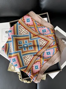Detail of silk-like scarf with geometric patterns and retro colors on a black tray