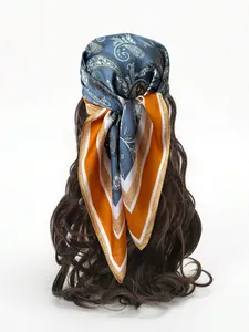 Blue and orange paisley silk-like scarf worn as a hair accessory on long brown hair