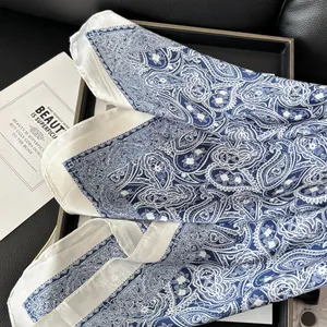 Blue paisley silk scarf with white patterns on black leather and card background