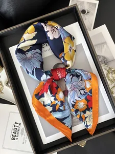 Détail d'un foulard en soie à imprimé fleuri bleu marine avec des bords orange