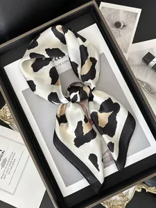 Detailed view of elegant leopard print silk scarf on a black tray with luxury props