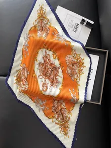 Detail of pleated silk square scarf with orange horse print and dark blue scalloped edges