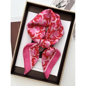 Silk square scarf with red and pink heart patterns presented in a luxury gift box