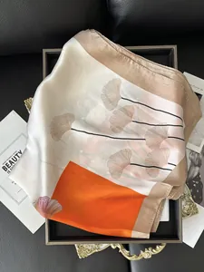 Nahaufnahme eines Seidenschals mit Ginkgo-Blattmustern und orangefarbenen Akzentkanten