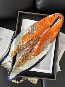 Detail view of a pleated scarf with orange crest prints and blue borders on a tray