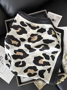 Macro shot of large leopard print silk scarf with black wide border on leather tray
