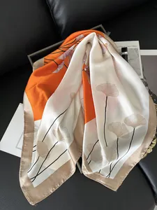 Detailstruktur eines Seidenschals mit Ginkgoblatt-Muster in Orange und Creme auf Leder