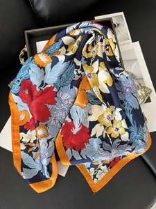 Gros plan d'un foulard en soie fleurie avec bord orange et texture lisse brillante