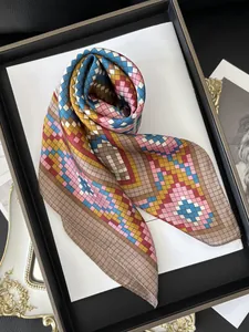 Detailed view of silk square scarf featuring colorful geometric patterns on a wooden tray