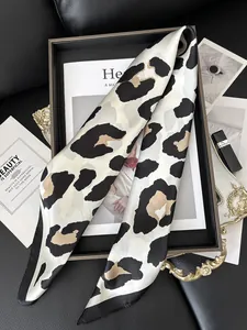 Detail of leopard print silk twilly scarf styled with fashion magazine and accessories
