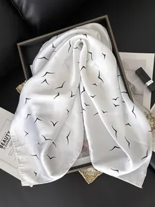 Detail of white silk scarf with black bird patterns on a high-end luxury backdrop