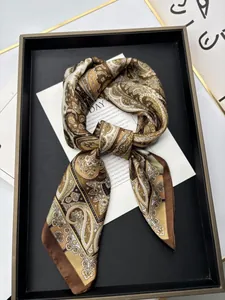 Close-up of silk-textured bohemian scarf with golden paisley patterns on a black tray