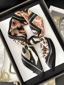 Detail of silk-like leopard print neck scarf with geometric patterns and rolled edges