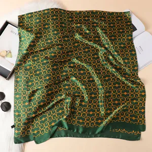 Detail of dark green silk scarf featuring orange geometric chain patterns and smooth texture