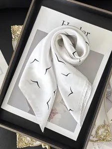 Close-up of elegant white silk scarf with minimalist black bird print on a magazine