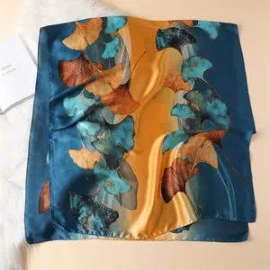 Detail of silk scarf with artistic yellow ginkgo leaf patterns on dark blue fabric
