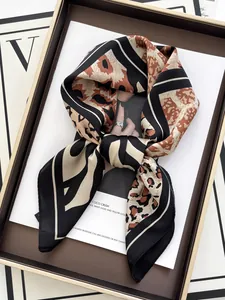 Close-up of elegant leopard print silk scarf with geometric borders in a gift box
