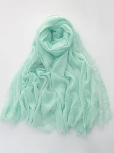 Close-up of mint green cotton linen scarf with natural crinkle texture and fringe trim