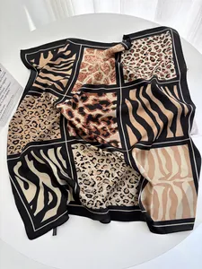 Flat lay of a leopard and zebra print silk scarf with black borders on a white table