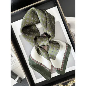 Elegante pañuelo de seda verde con patrones circulares retro en bandeja negra