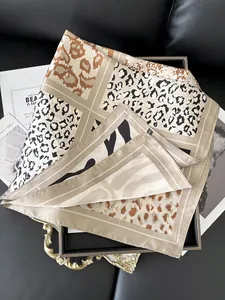 Detail of 100% silk scarf featuring leopard and zebra animal prints on a metal tray