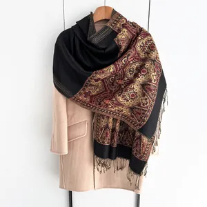 Close-up of ethnic paisley print scarf with black fringe tassels on a pink coat