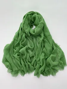 Detail of light green cotton linen scarf with rich pleated texture and frayed edge trim