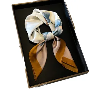Eleganter Seidenschal mit blauem Ginkgoblattmuster und Farbfeldern in einer Geschenkbox