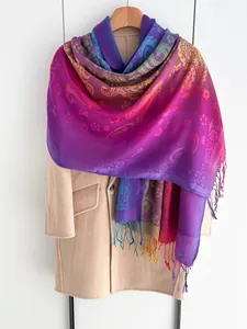 Detail van boho sjaal met regenboogverloop, paisley-motieven en kleurrijke franjes