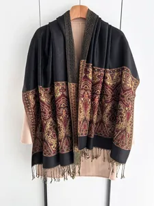 Detail of ethnic jacquard pattern and tassel fringe on black winter shawl scarf
