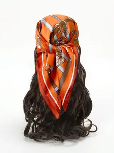 Close-up of orange silk scarf featuring vintage equestrian motifs and chain patterns