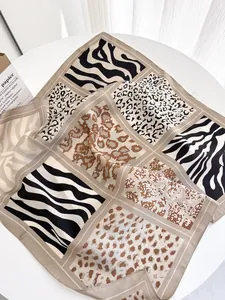 Detailed close-up of leopard and zebra print silk scarf textures on a white table