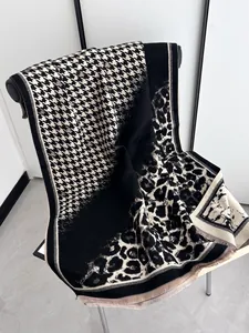 Close-up of leopard and houndstooth patterned scarf with fringe details and thick knit texture